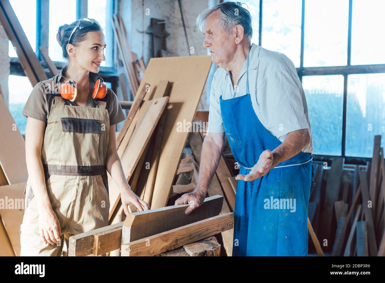 Senior carpenter sharing wisdom with younger aspiring woman colleague Stock Photo