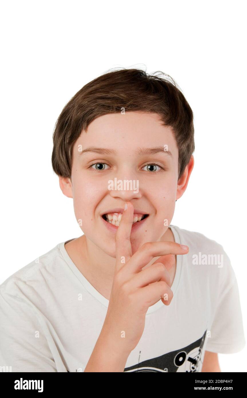 Frontale Kopf-und-Schultern-Ansicht eines 10-jhrigen kaukasischen Jungen vor weißem Hintergrund sich den rechten Zeigefinger auf den offen lächenden M Stock Photo