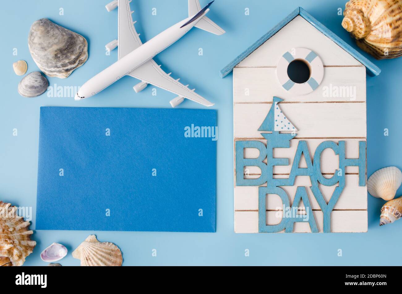 Empty blue paper with seashells and decorative airplane. Summer travel concept. Top view or flat lay. Copy Space. Stock Photo