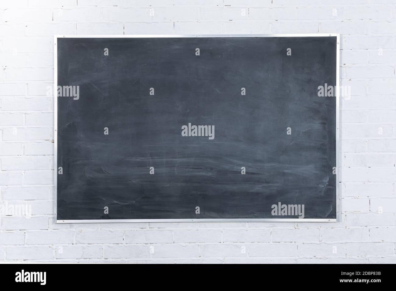 White brick wall. It's written in white chalk on a blackboard - two plus two equals four. The basics of arithmetic start with the youngest grades in every school in the world. Stock Photo