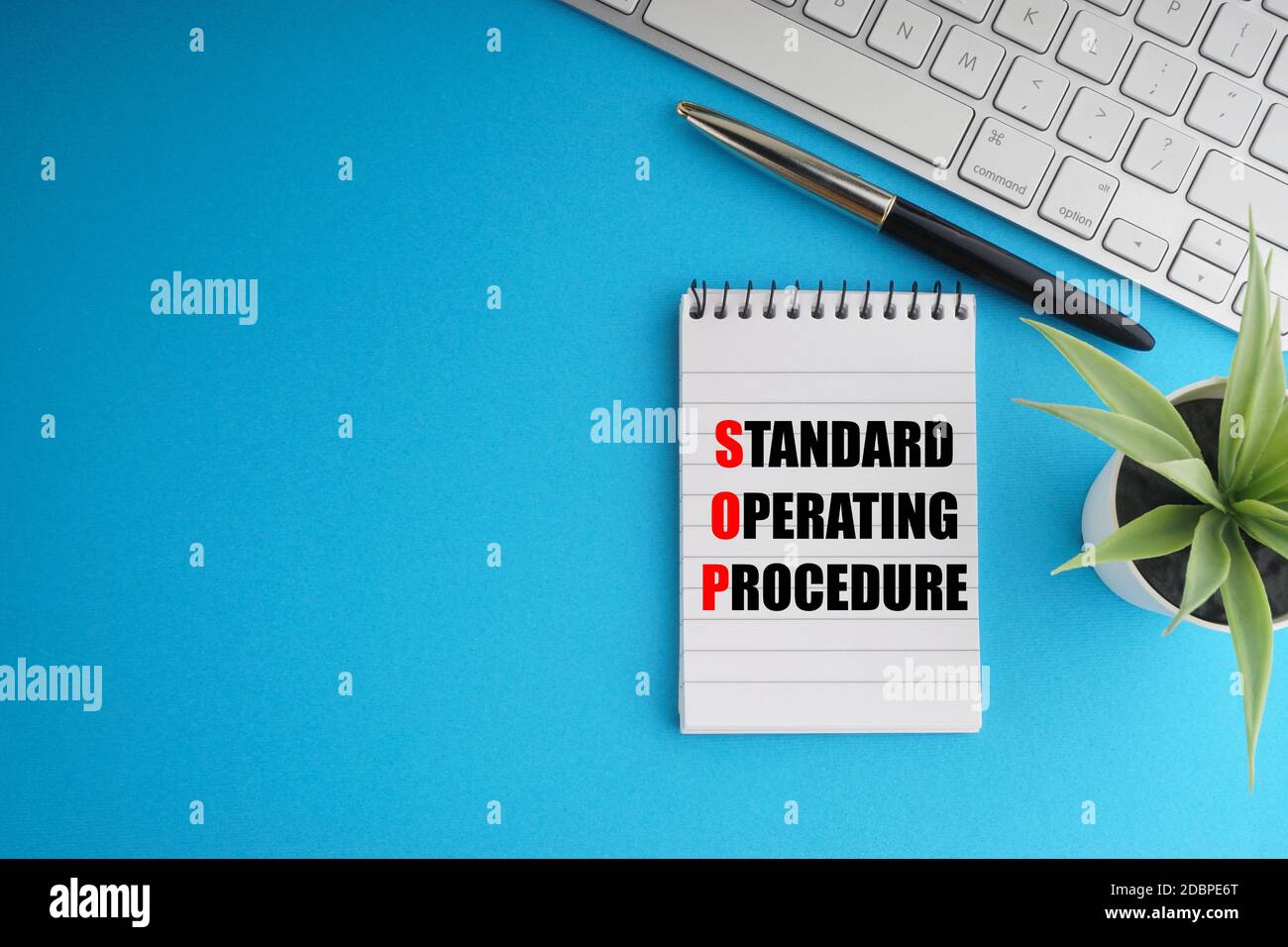 STANDARD OPERATING PROCEDURE text with fountain pen, notepad, decorative plant and keyboard on blue background. Coronavirus Covid19 and Business Conce Stock Photo