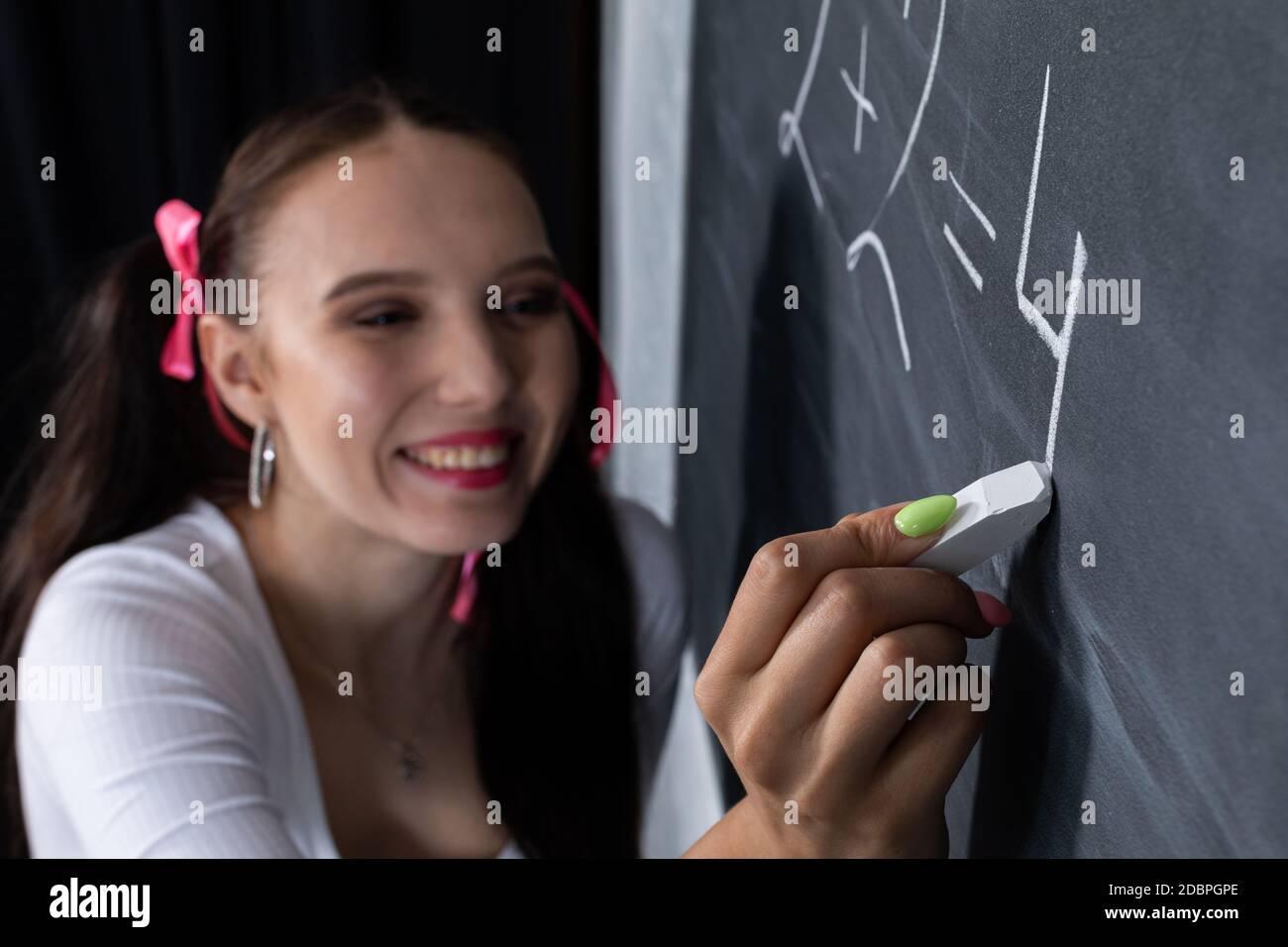 A young schoolgirl writes on the blackboard. School math lesson. He ...