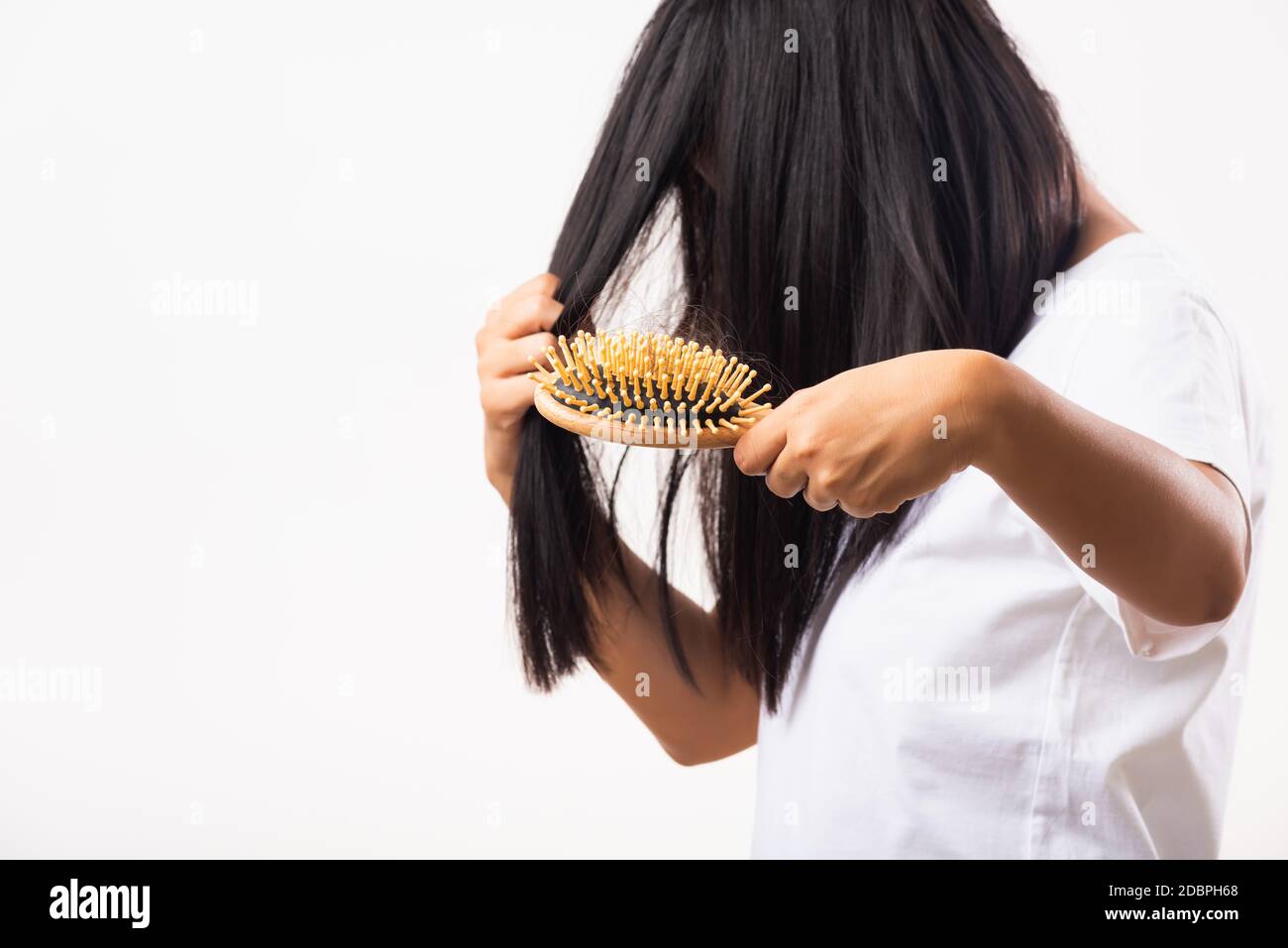 Asian woman unhappy weak hair she shows hairbrush with damaged long loss hair in the comb brush on hand, studio shot isolated on white background, med Stock Photo
