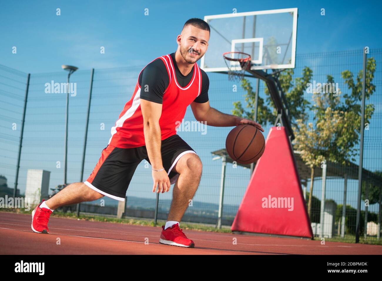 The young basketball player in red sportswear is playing streetbasket or  basketball outdoors Stock Photo - Alamy