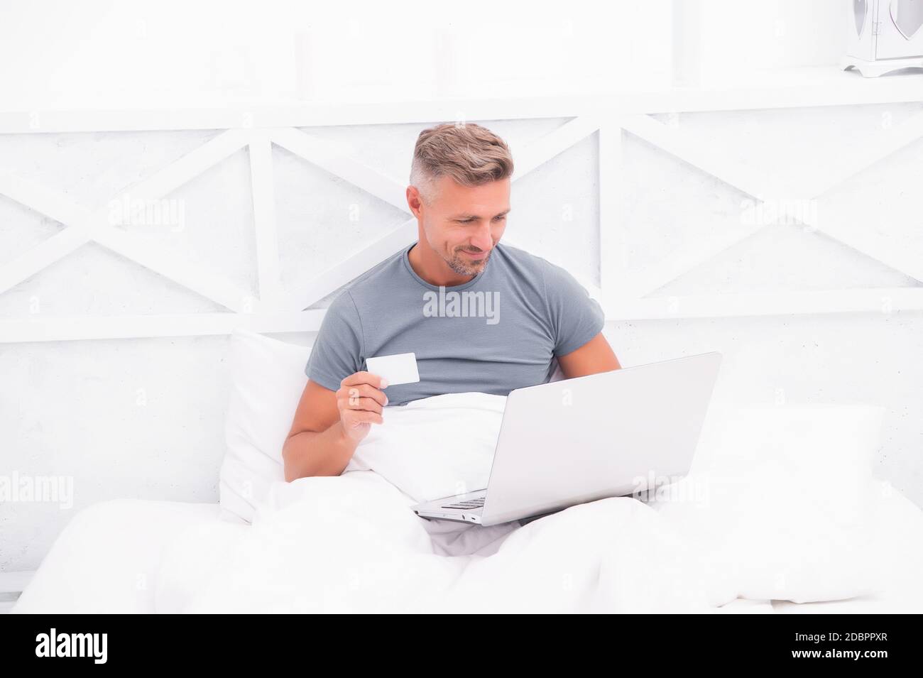 Payment and purchase. Online shopping. Work from home. Checking messages. Mature guy pajamas in bed. Businessman with computer. Hipster work on laptop. Bedroom rest. Remote job. Online communication. Stock Photo