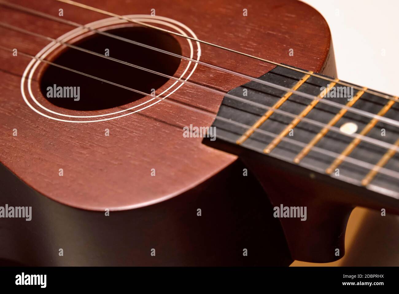Classical brown ukulele showing sound hole, strings, and fretboard