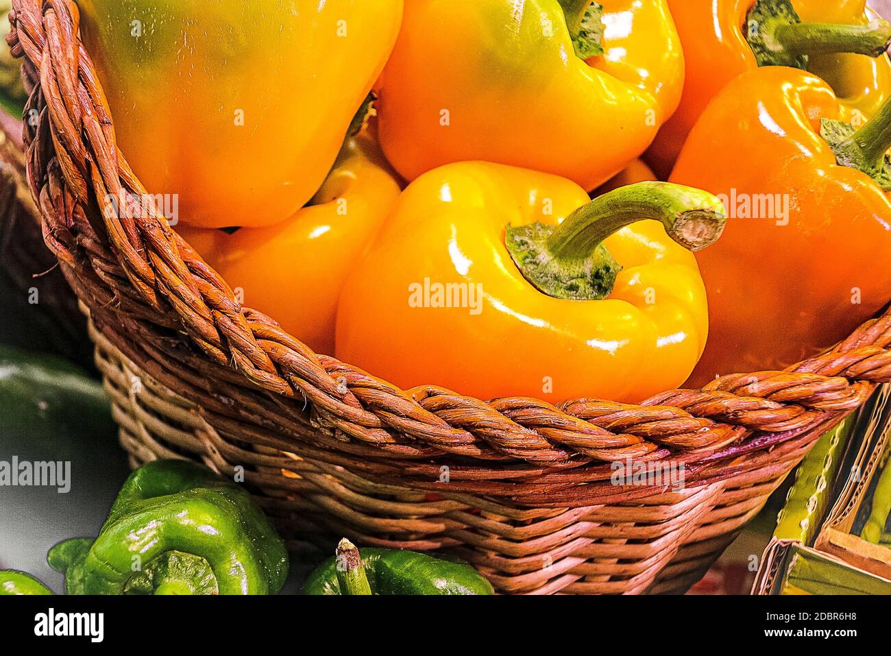 Raw Organic Orange and Yellow Fresh Bell Peppers in red basket Stock Photo