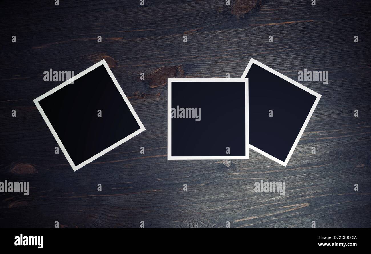 Three blank square photo frames on wood table background. Top view. Flat lay. Stock Photo