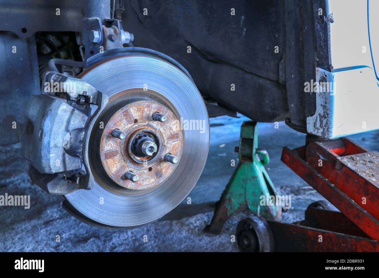 Front disc brake on car in process of new tire replacement. The rim is