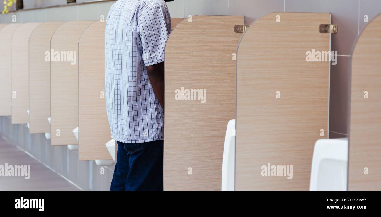 The man peeing in male toilet urinals bowl in restroom, wc Stock Photo