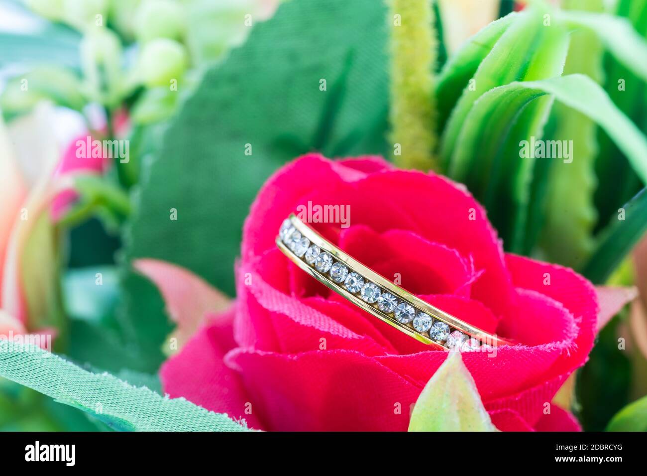Diamond wedding ring resting in a fake rose flower close up Stock Photo ...