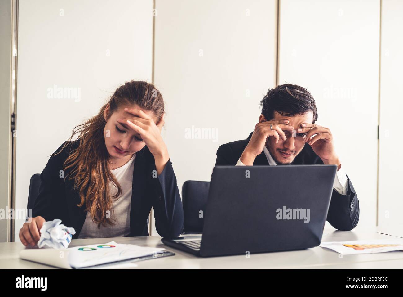 Unhappy serious businessman and businesswoman working using laptop computer on the office desk. Bad business crisis situation and bankruptcy concept. Stock Photo