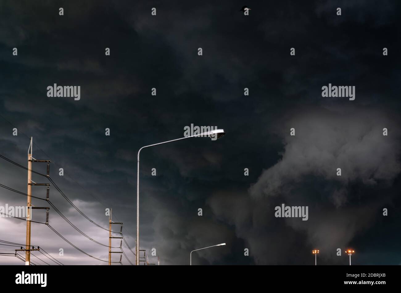 Stormy sky with street light pole and three-phase electric pylons ...