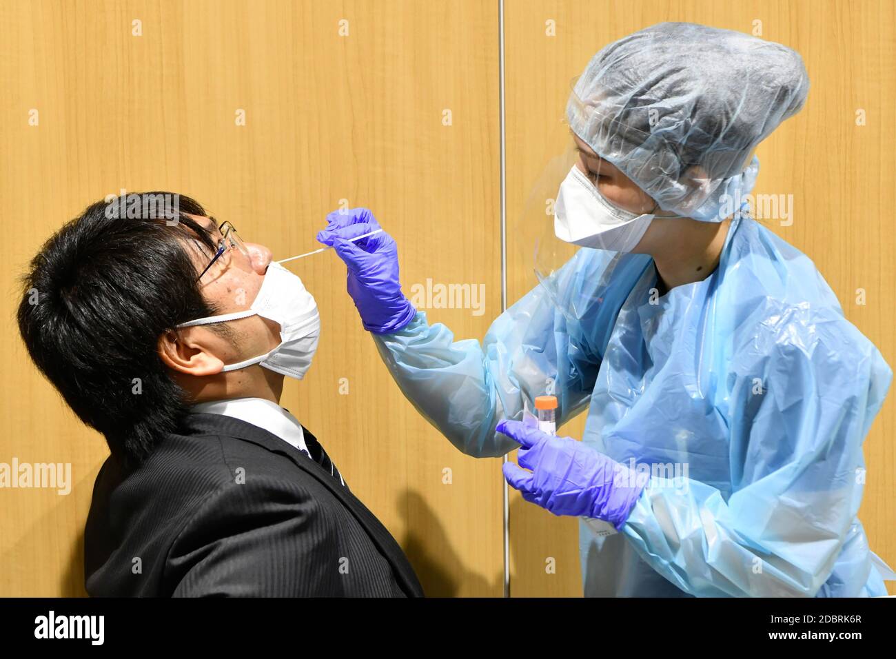 A nurse (R) demonstrating sample collection in the PCR center at Narita Airport's Terminal 2 on