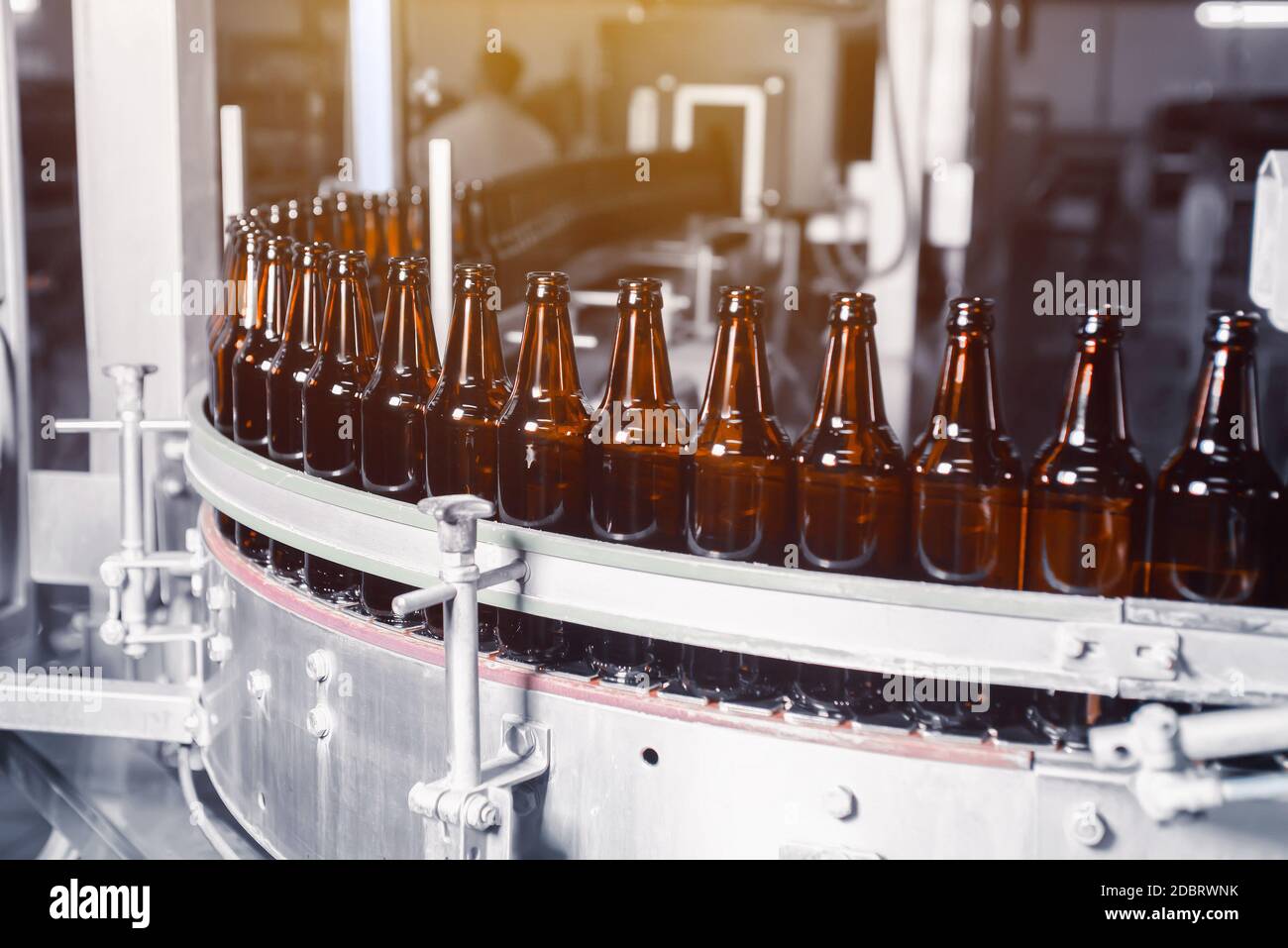 Glass beer bottles of brown color on the conveyor line of beer bottling