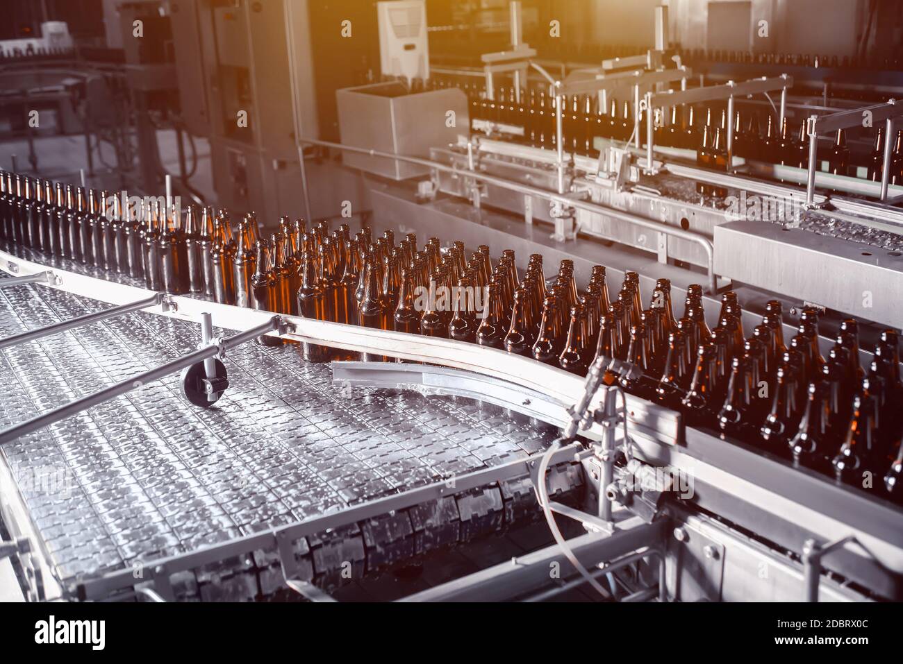 Glass beer bottles of brown color on the conveyor line of beer bottling close up Stock Photo