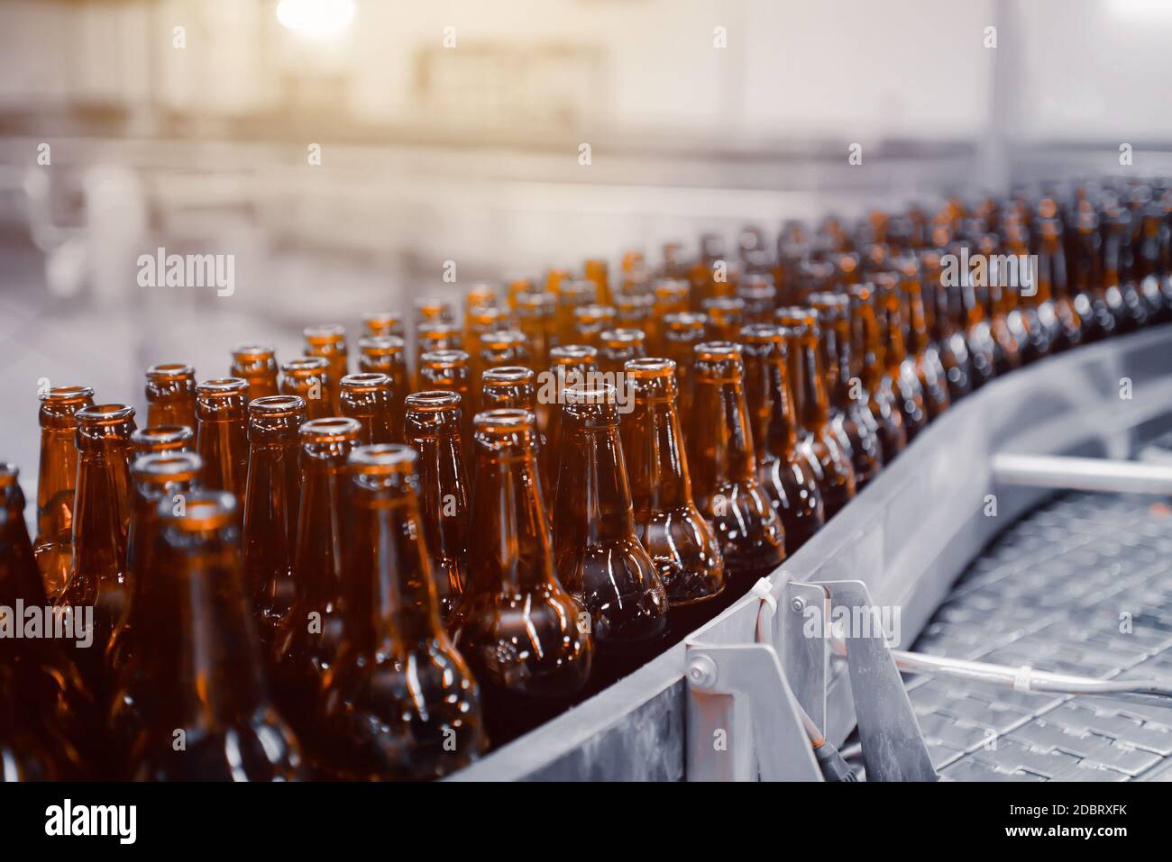 Glass beer bottles of brown color on the conveyor line of beer bottling