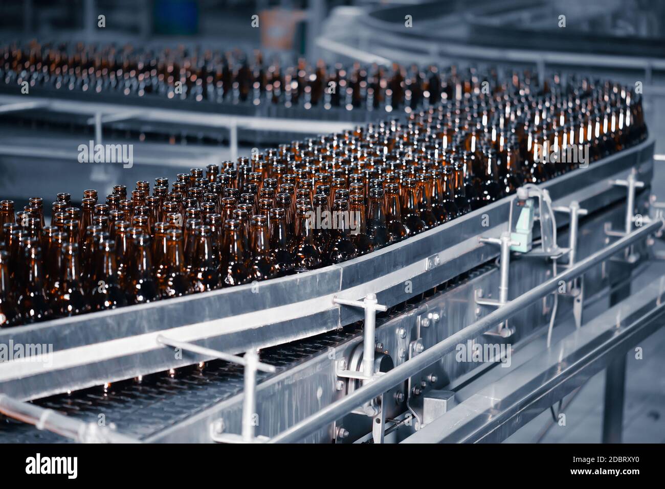 Glass beer bottles of brown color on the conveyor line of beer bottling close up Stock Photo