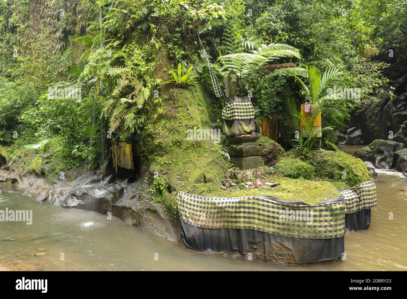River and ancient hindu altar and Goa Giri temple in the forest Beautiful river flow surrounded by wild rainforest on a sunny summer day. Bali, Indone Stock Photo