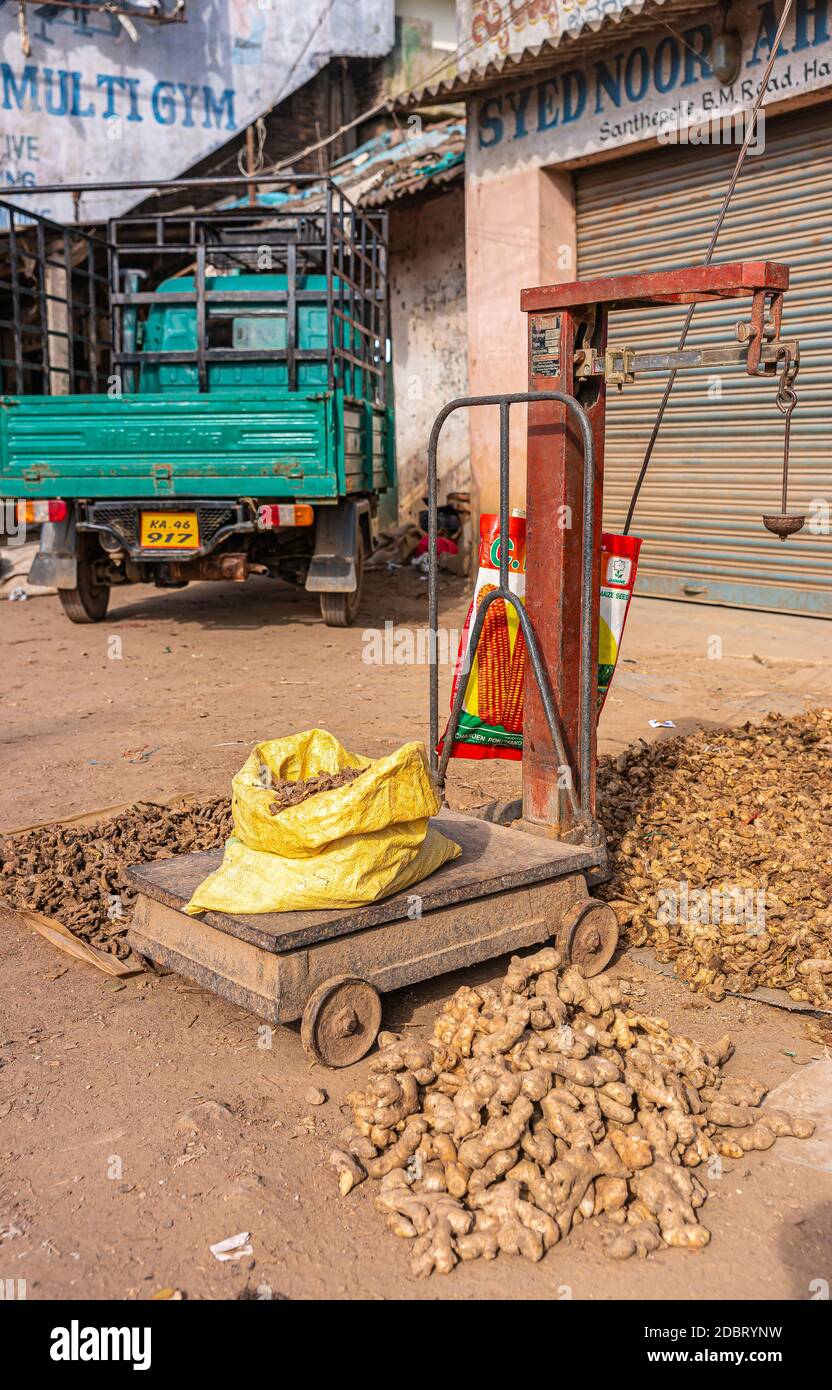Hassan, Karnataka, India - November 3, 2013: Heavy scale whereon yellow bag with ginger roots is weighted. Light green  pickup truck and heaps of more Stock Photo