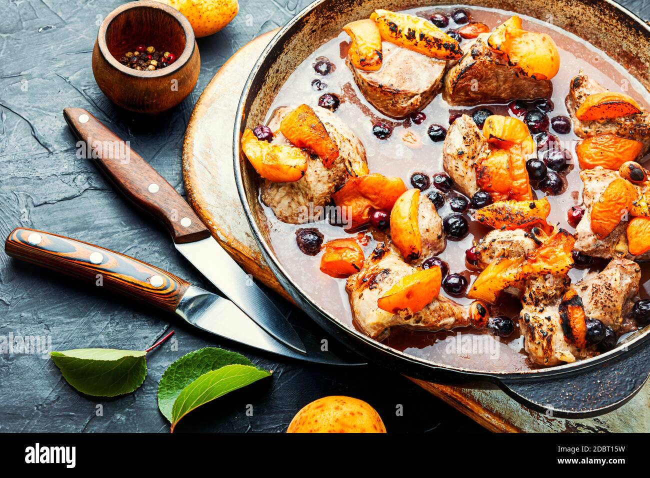 Baked meat in red wine with apricot and blackcurrant.Stewed pork in iron  cast pan Stock Photo - Alamy