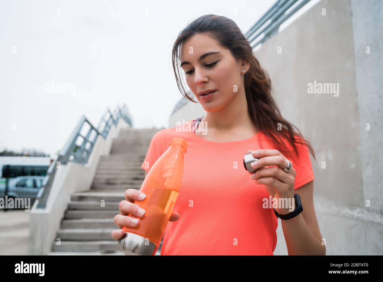 Athletic woman drinking water after training Stock Photo - Alamy