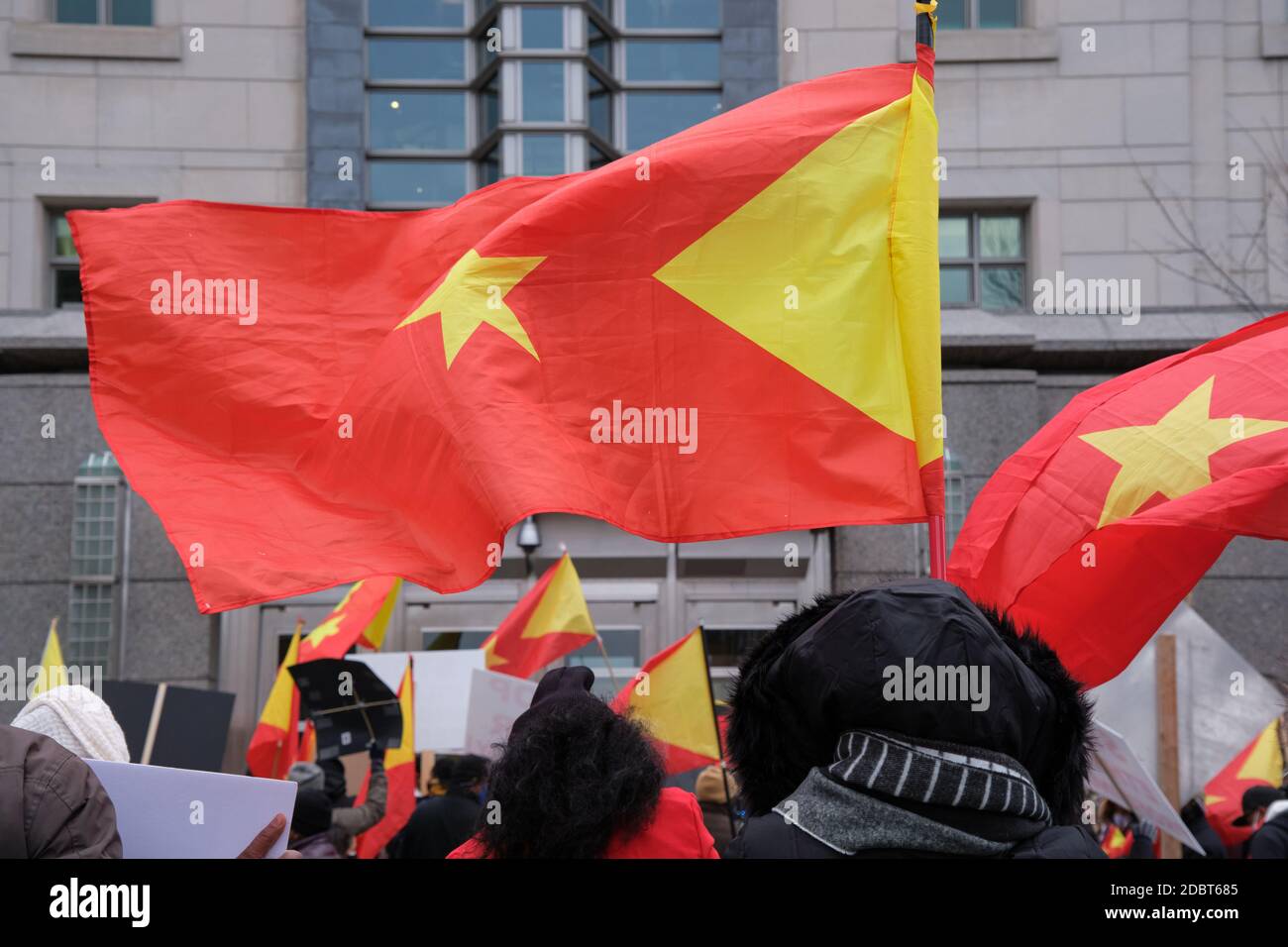 Faceless Protesters flying the flag of Tigray in front on an embassy building Stock Photo