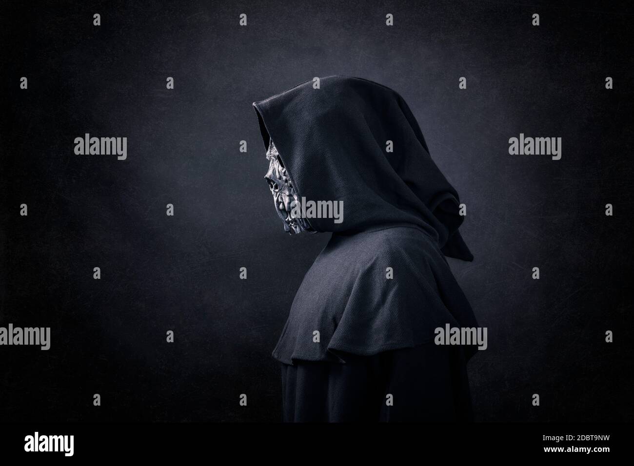 Scary figure in hooded cloak in the dark Stock Photo - Alamy