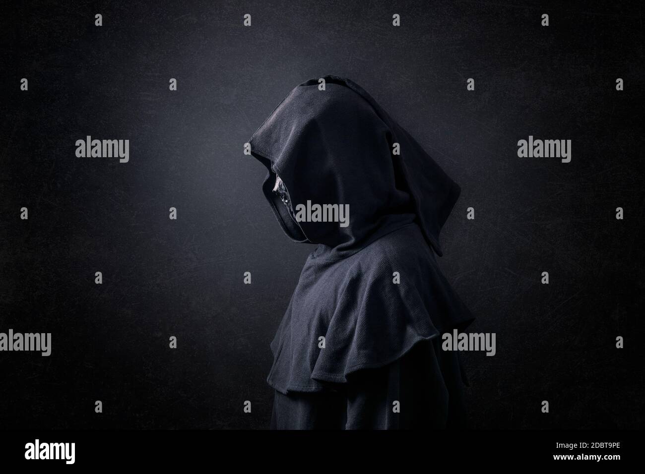 Scary figure in hooded cloak in the dark Stock Photo - Alamy