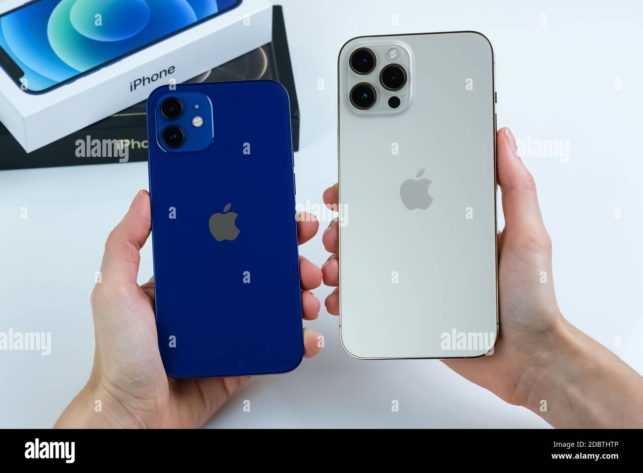 Iphone 12 Pro Max In Gold Next To Iphone 12 In Blue On A White Desk Stock Photo Alamy