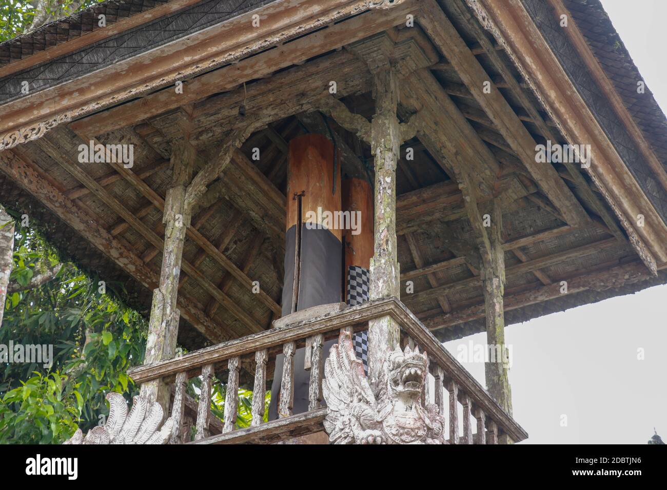 Wooden bell with a mallet made from a tree trunk. Bale Kulkul is building to hand up the traditional alarm for local Balinese people when they are inv Stock Photo