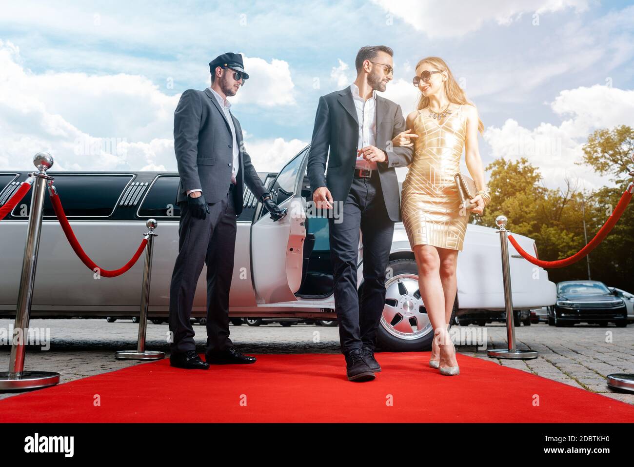 Couple arriving with limousine walking red carpet, a driver is opening the car door Stock Photo