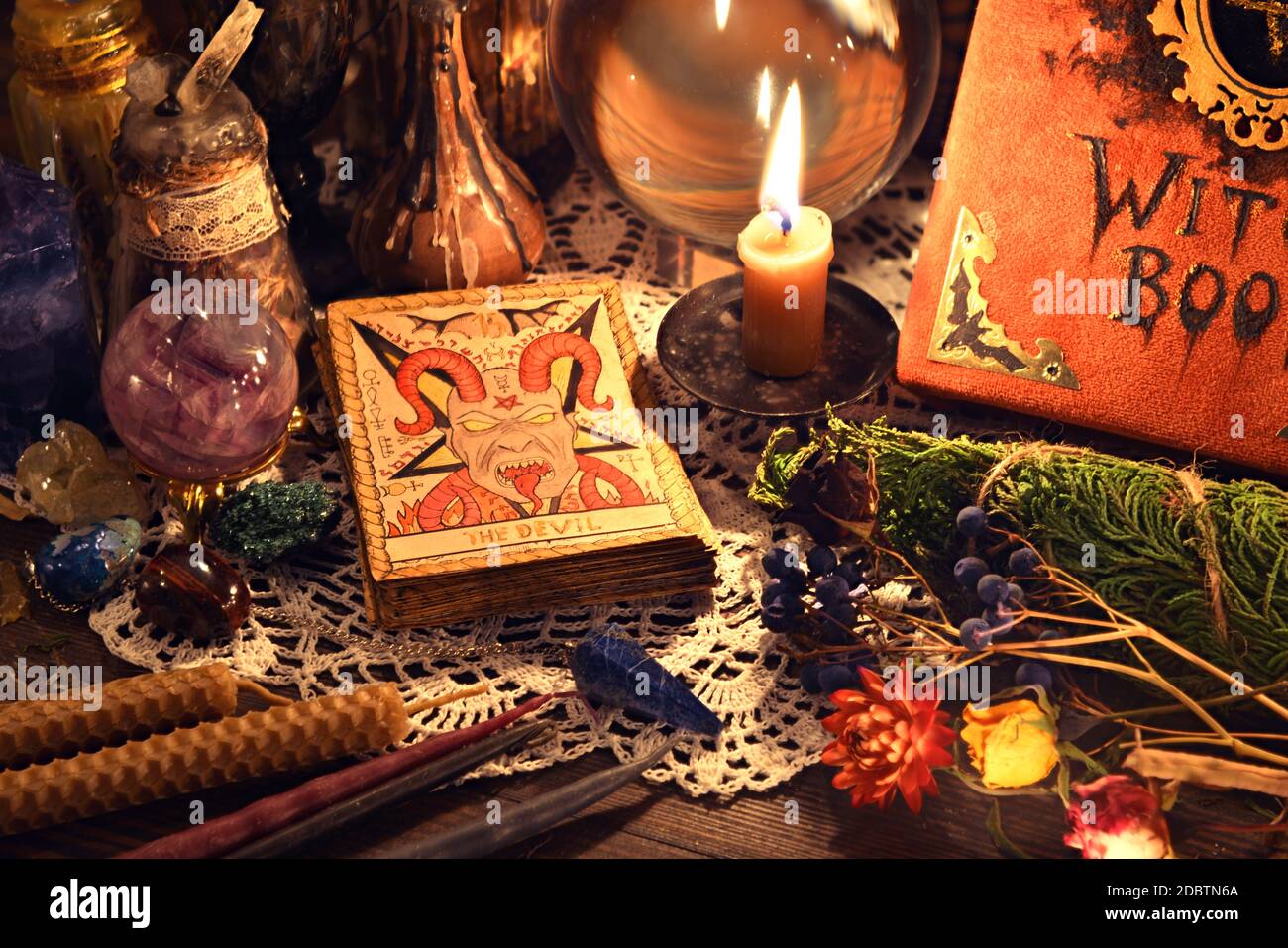 Still life with tarot card Devil, witch book, crystal ball, candle and  herbs on wooden table. Esoteric, wicca and occult background, fortune  telling a Stock Photo - Alamy