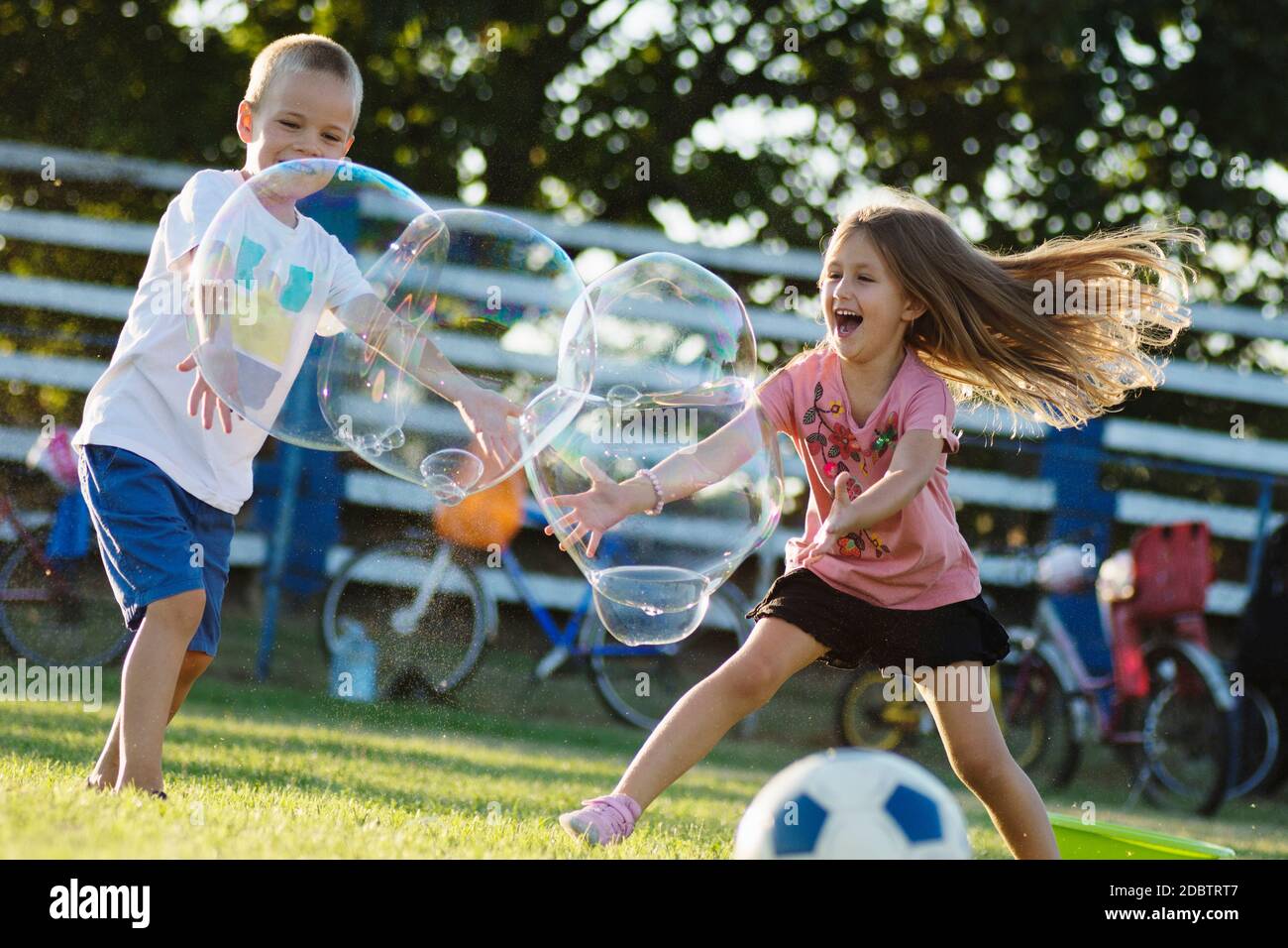 Playful happy children are playing with giant soap bubbles outdoors ...