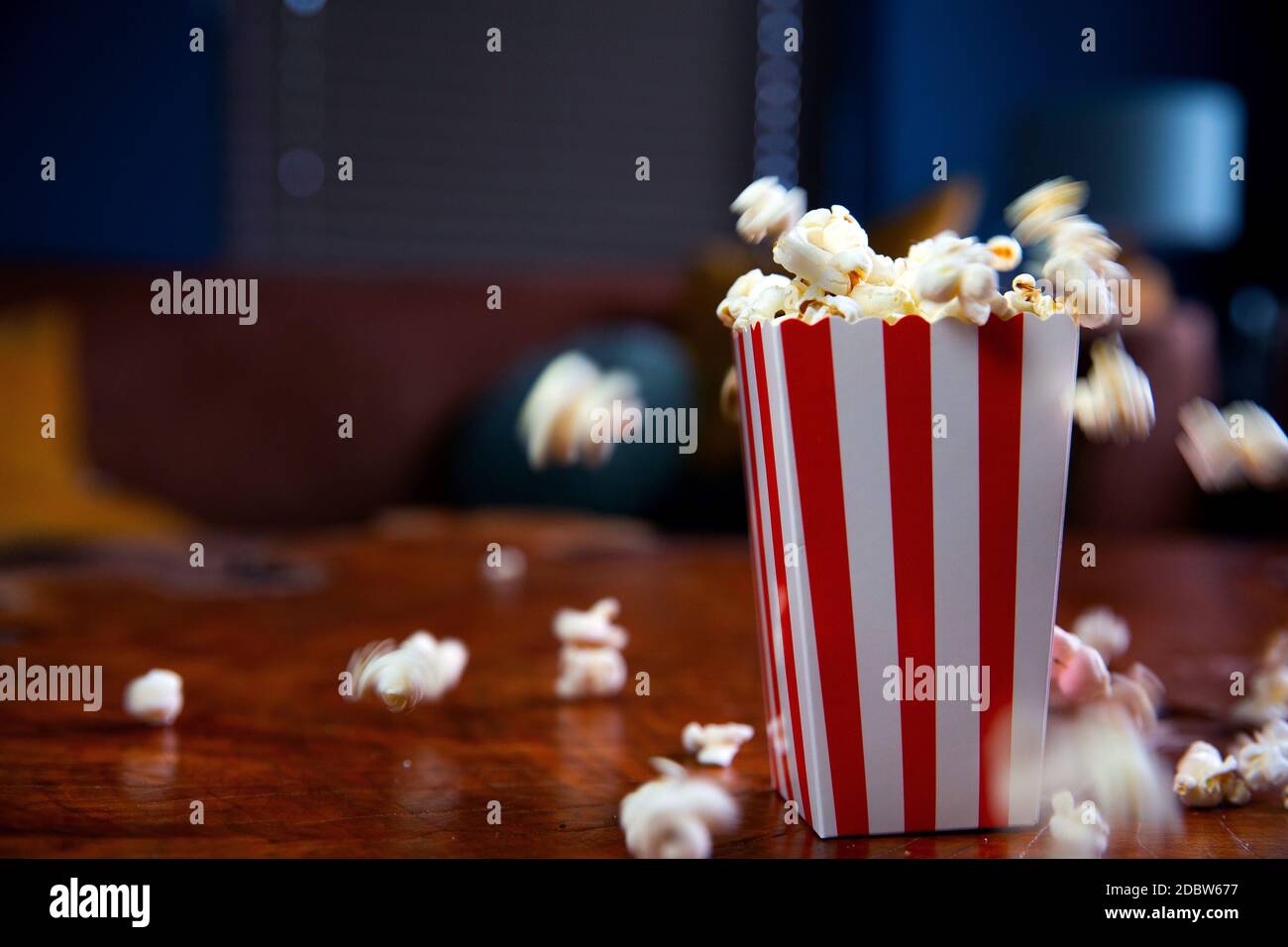 Popcorn flying out of cardboard box. red and white striped popcorn bucket  with flying popcorn in the living room, movie or cinema concept food or  snac Stock Photo - Alamy