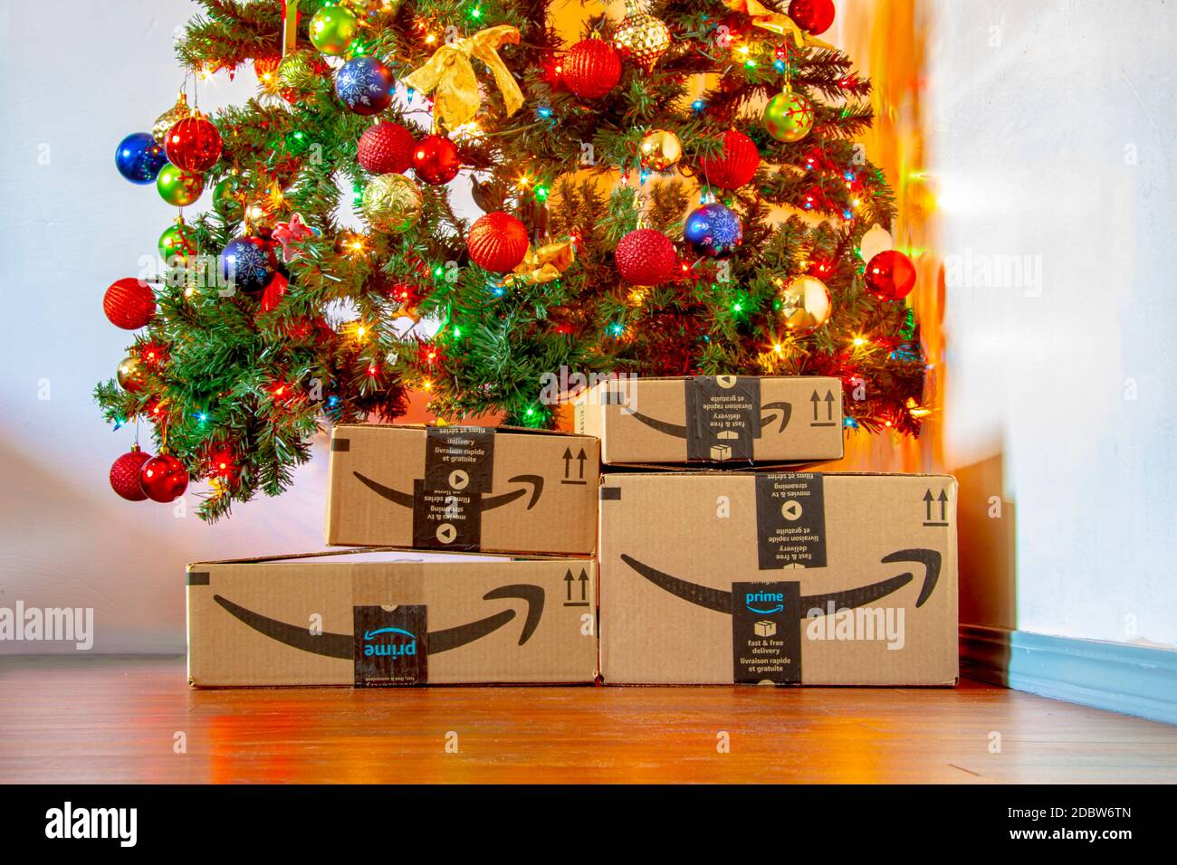 Calgary, Alberta, Canada. Nov. 16, 2020. Amazon boxes under a Christmas tree with ornaments and lights on. Concept: Shopping during the holidays. Stock Photo