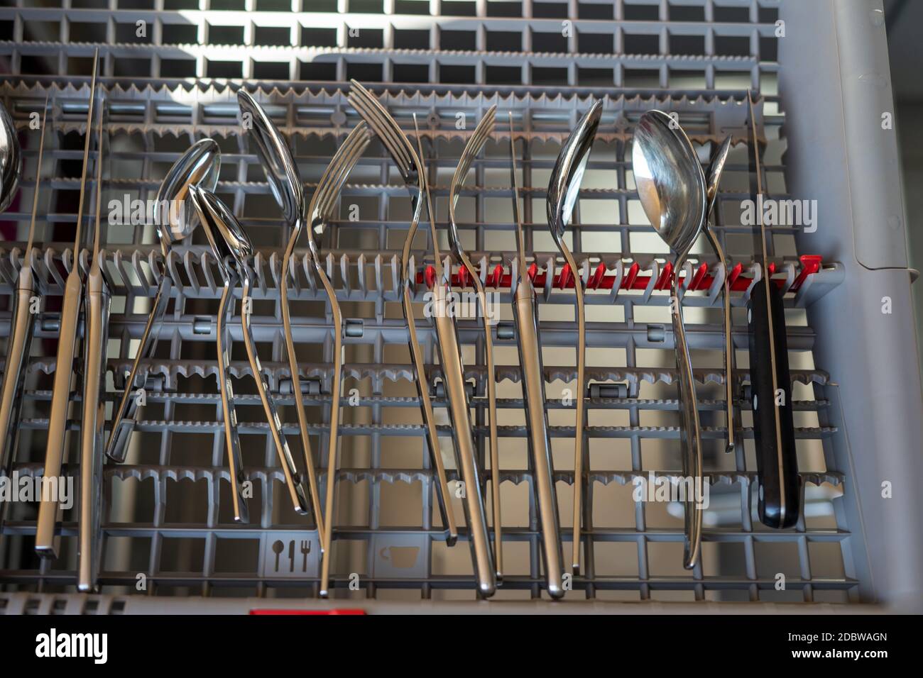 open dishwasher in which the cutlery drawer is open. forks knife and