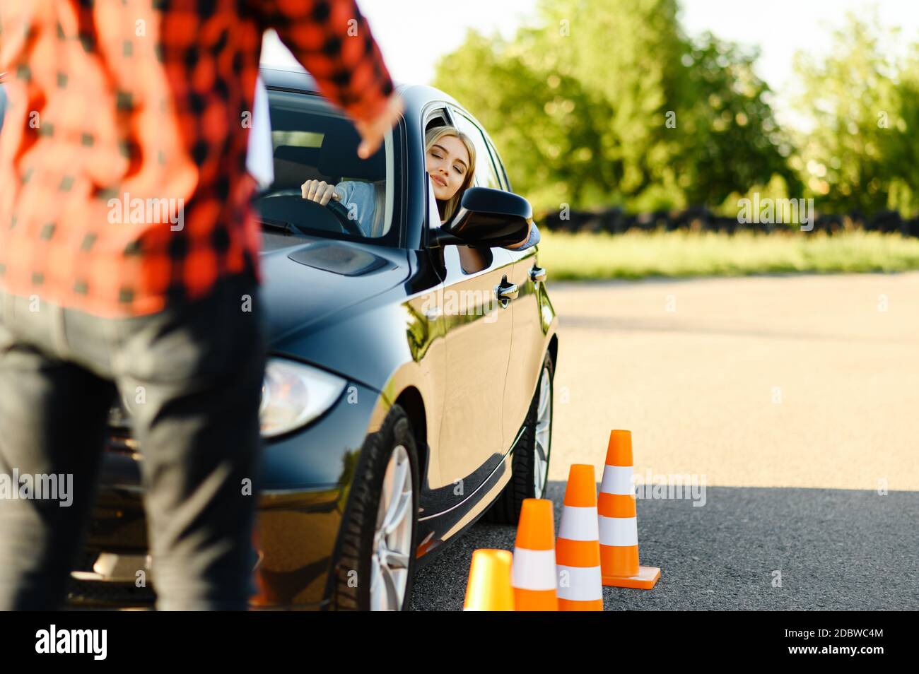 Male instructor and woman in car, traffic cones, lesson in driving