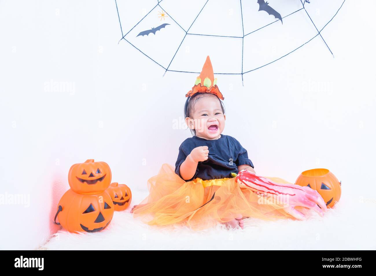 Funny Happy Little Cute Baby Girl In Halloween Costume With Pumpkin Jack With Cobweb And Black Balloon In Home Halloween Party On White Wall Backgroun Stock Photo Alamy