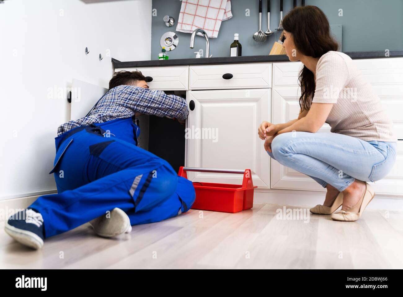 Plumber Cleaning Drain And Pipe In Kitchen Stock Photo