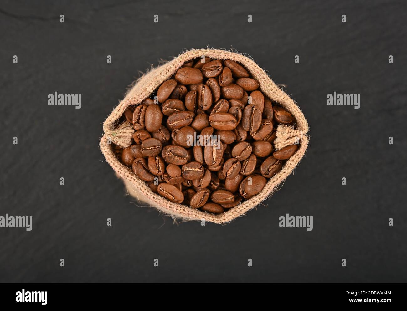 Close up one jute canvas bag of roasted Arabica coffee beans over black ...