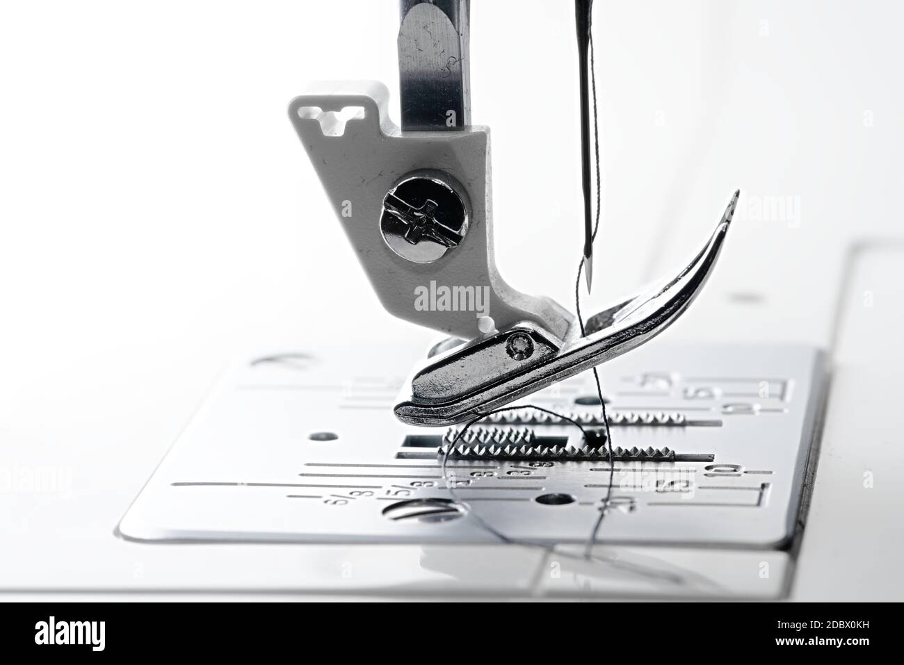 2 Needle point and thread in macro side view of sewing machine feed