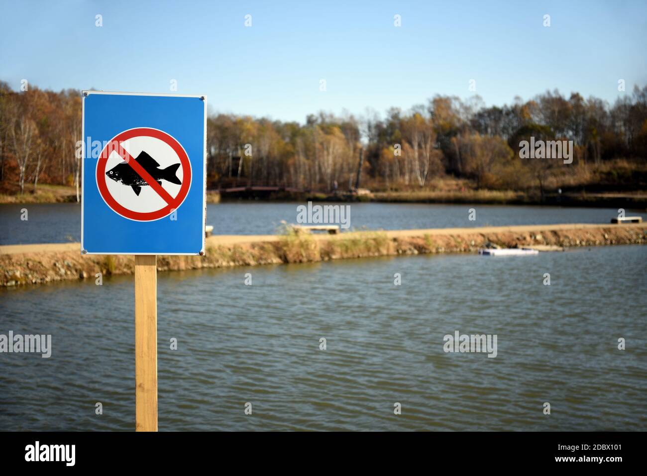 Prohibitory sign fishing is prohibited on background of two lakes and autumn forest in the park. Stock Photo