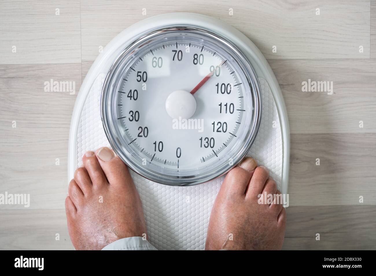 Man Feet On Weight Scale. Obesity And High Cholesterol Stock Photo