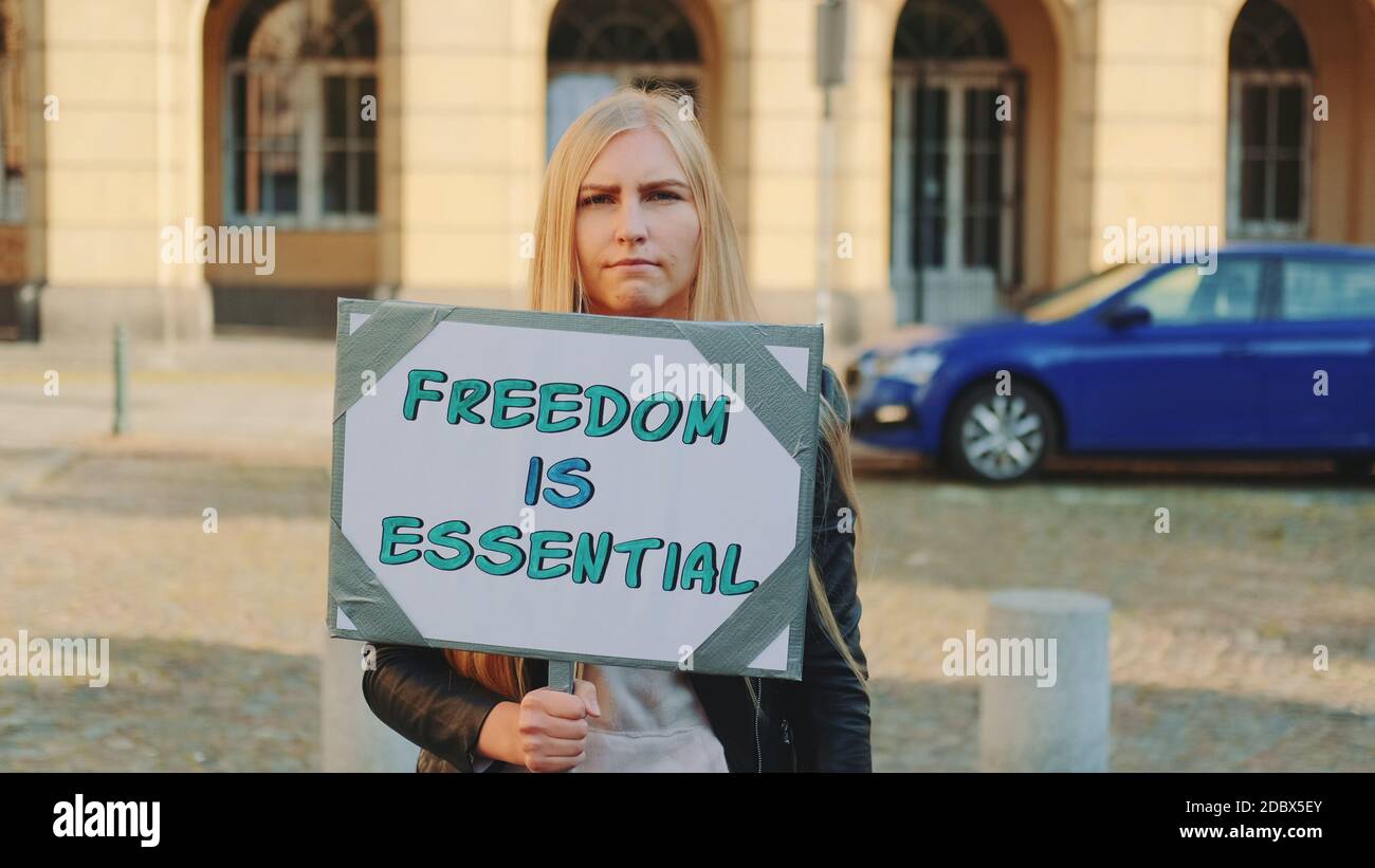 Woman on protest walk calling that freedom is essential by walking on the street with banner. Stock Photo