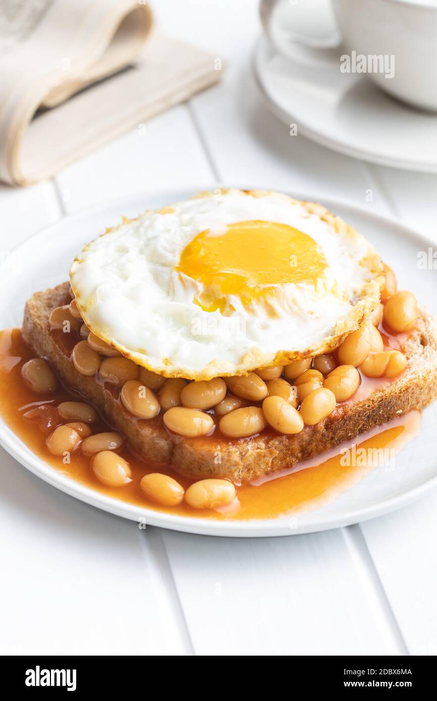 Toast with fried egg and baked beans on plate. Stock Photo