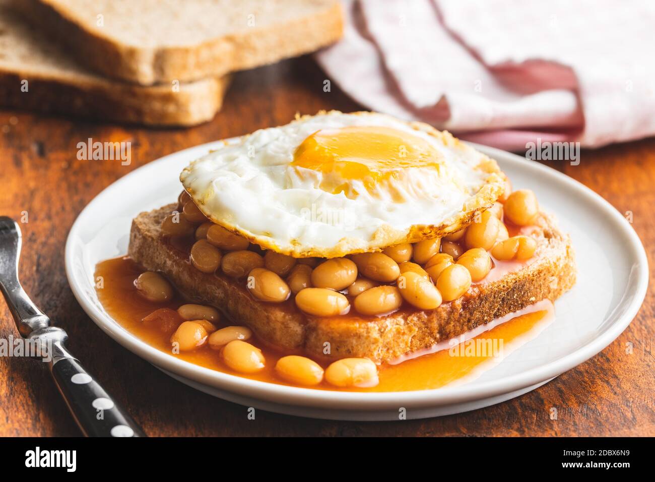 Toast with fried egg and baked beans on plate. Stock Photo