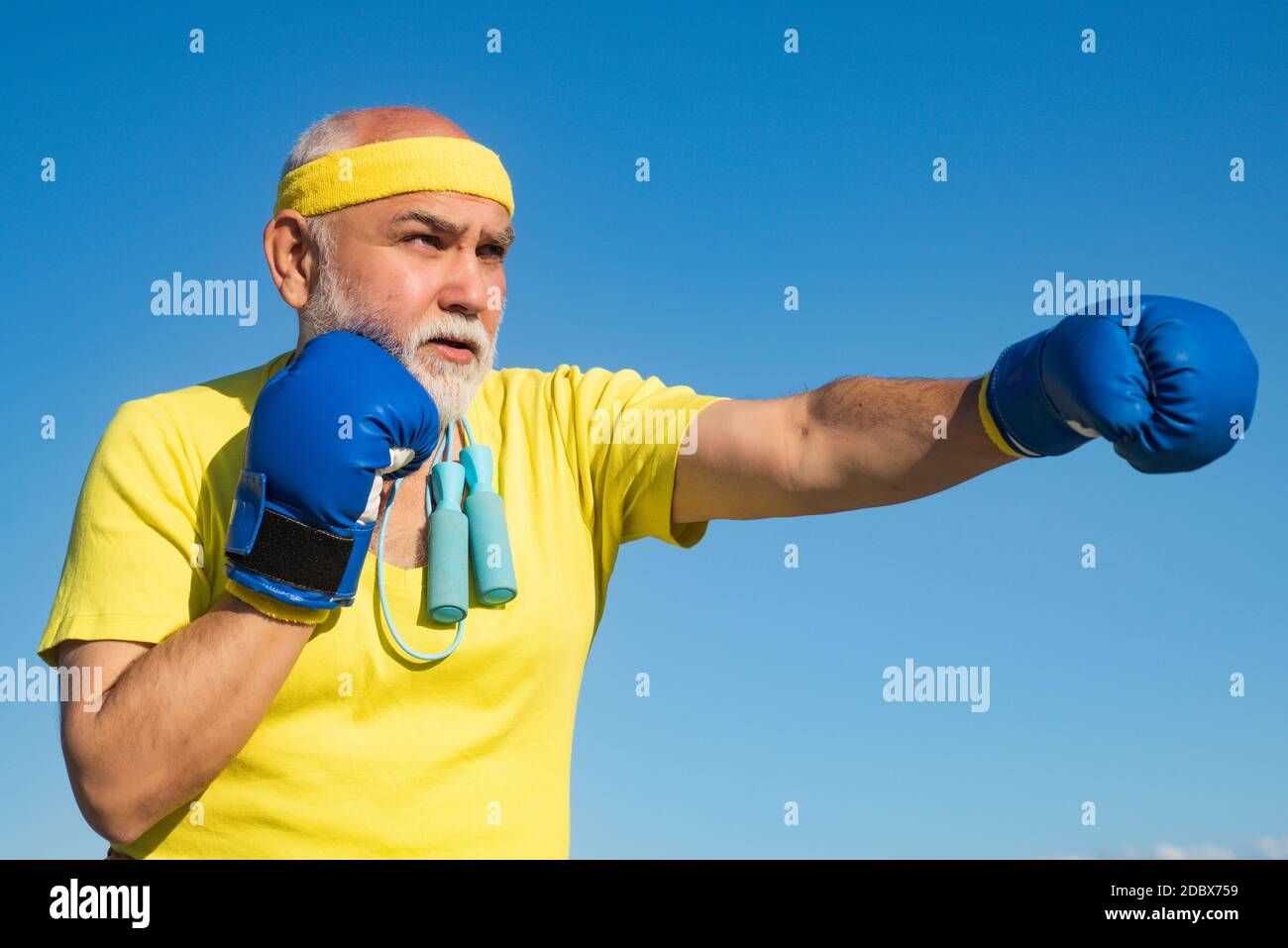 Senior sportive man in boxing stance doing exercises with boxing gloves