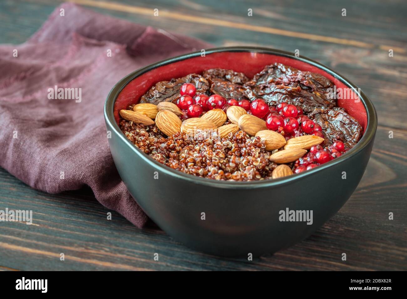 Bowl of red quinoa with olives, sun-dried tomatoes, berries and nuts Stock Photo
