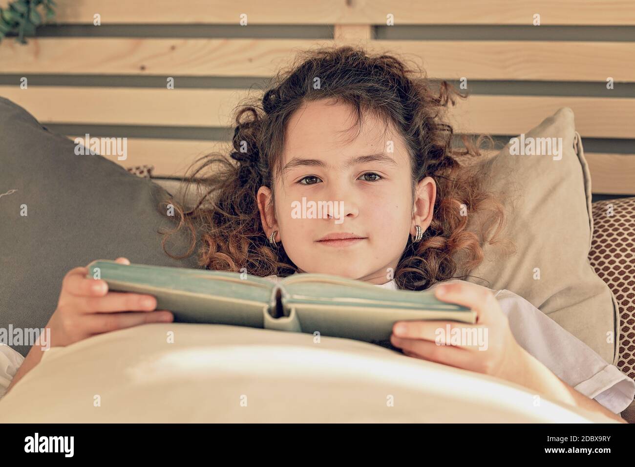 Close-up portrait young pretty caucasian girl and a book in bed. Positive emotions. Life style Stock Photo